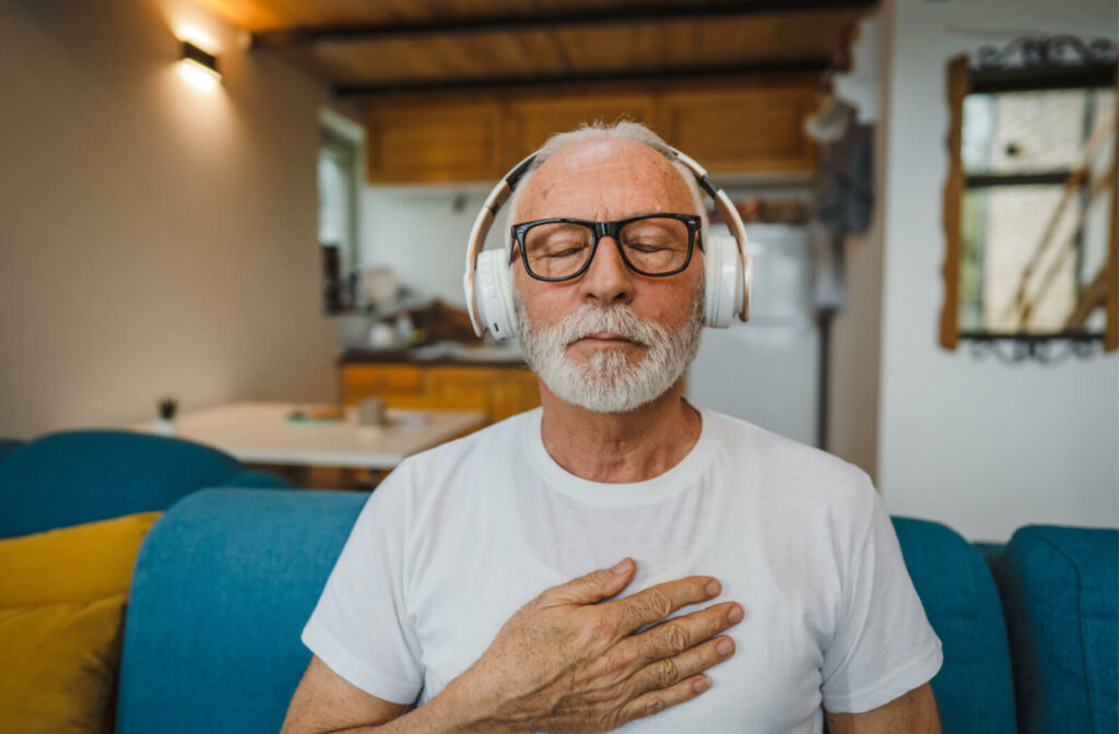 A senior man calmly listening to music using his headphones.