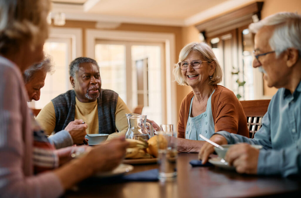 A group of older adults sitting around a table, eating and enjoying breakfast while smiling and chatting