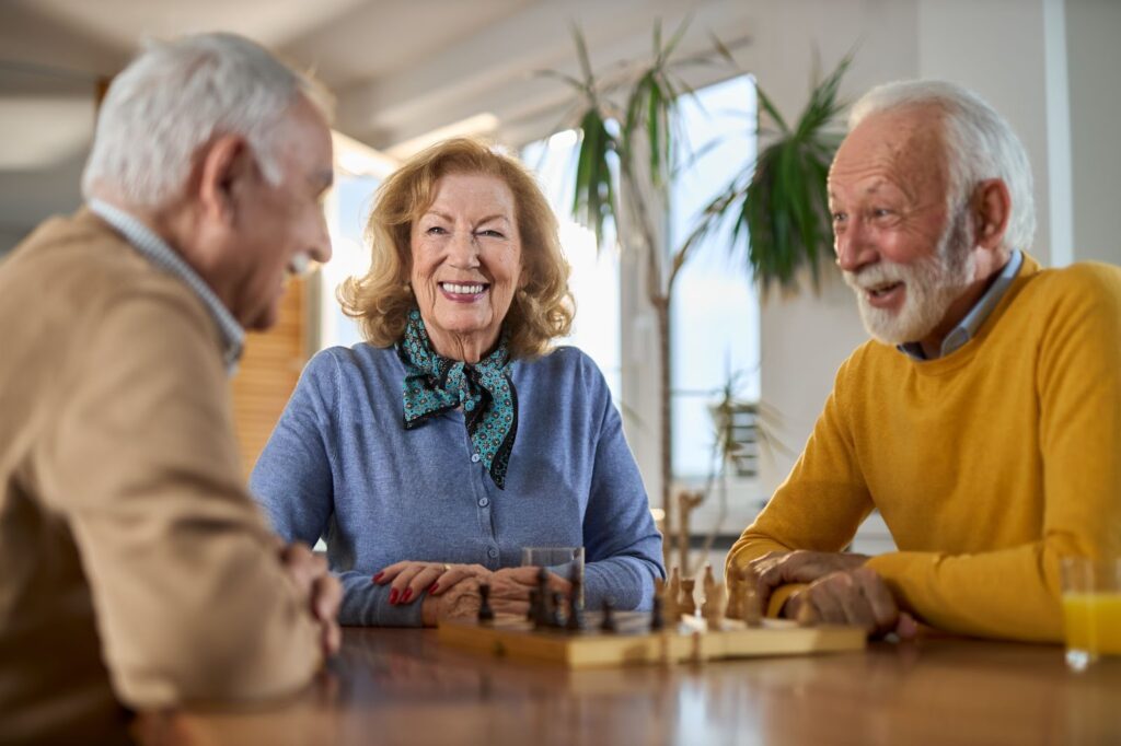 A group of happy seniors play chess in a peaceful apartment.