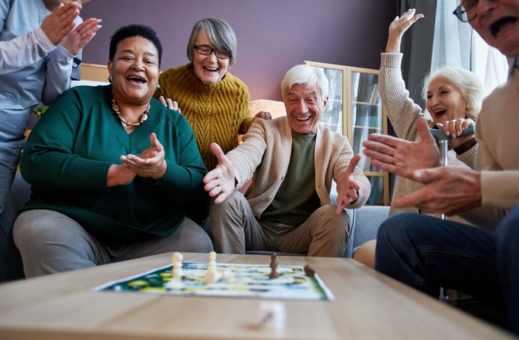 A group of seniors celebrate as they play a board game together.