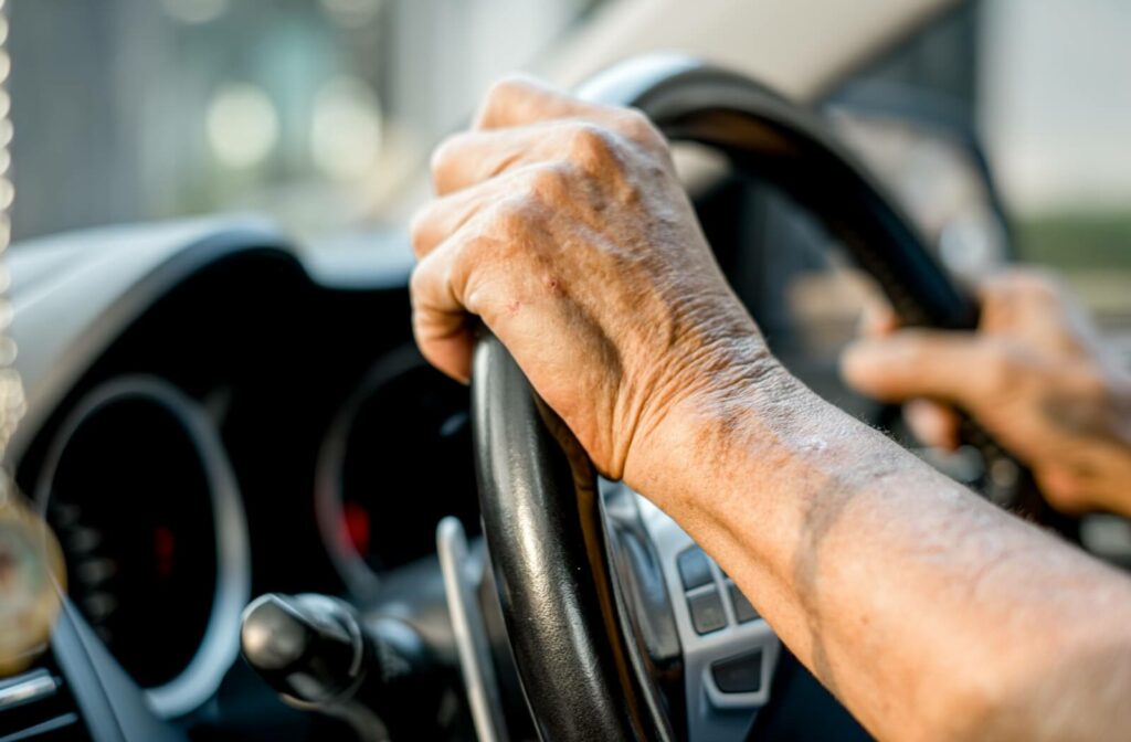 A close-up image of a senior demonstrating safe driving habits with their hands at the 10 and 2 o'clock positions on their steering wheel.