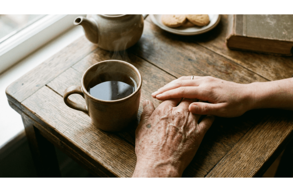 ea mug on a table, with a younger person's hand nearby offering support.